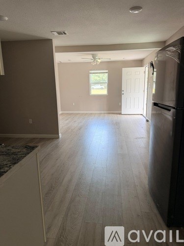 A kitchen with a refrigerator and a fan on the ceiling.