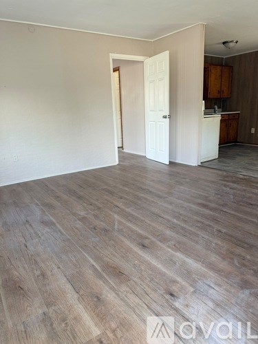 A room with wooden flooring and a white door leading to another room.