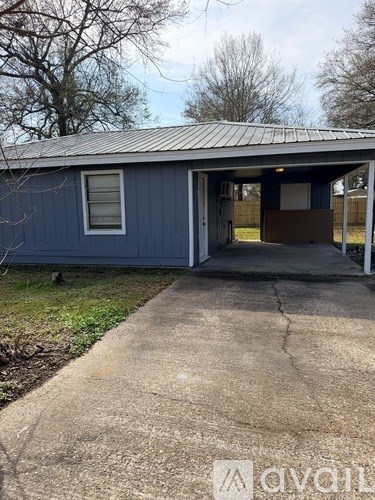 A blue building with a metal roof and a concrete walkway in front.