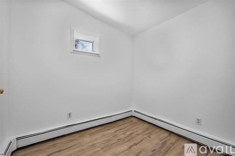 A room with a window and wooden flooring.