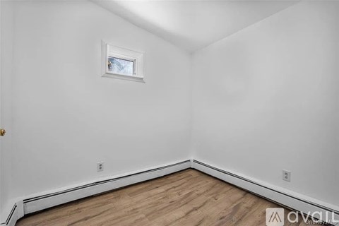 A room with a window and wooden flooring.