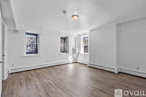 A spacious room with wooden floors and white walls.