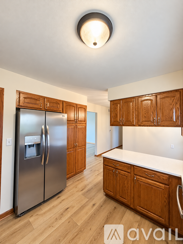A kitchen with wooden cabinets and a stainless steel refrigerator.