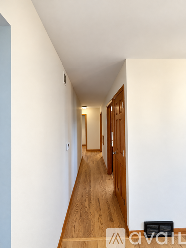 A long hallway with wood floors and white walls.