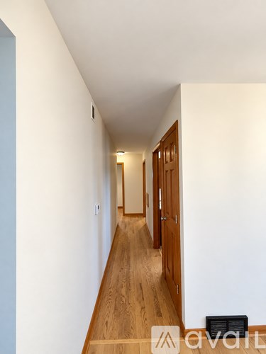 A long hallway with wood floors and white walls.