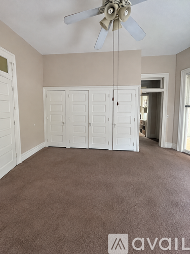 A room with a ceiling fan and carpeted floor.