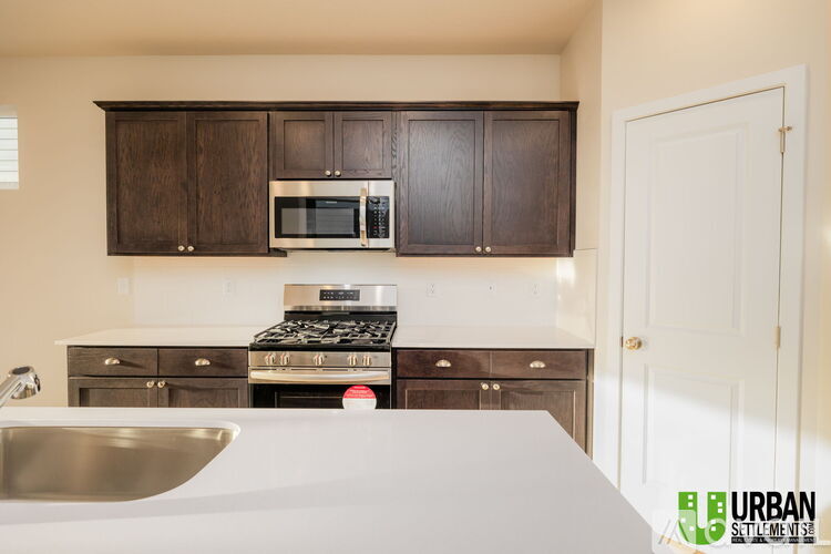 A kitchen with a white counter top and dark brown cabinets.