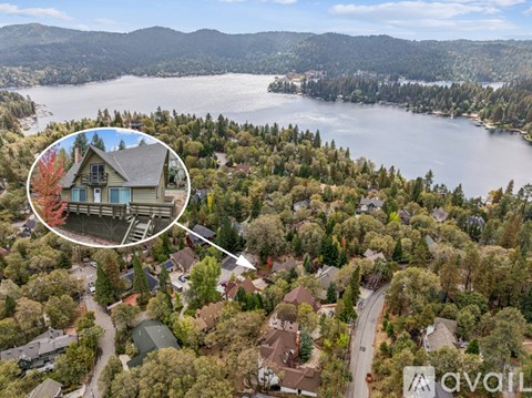 A bird's eye view of a neighborhood with a lake in the background and a house in the foreground.