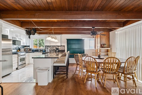 A kitchen with wooden floors and a dining table with chairs.