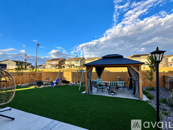A backyard with a gazebo and lawn chairs.