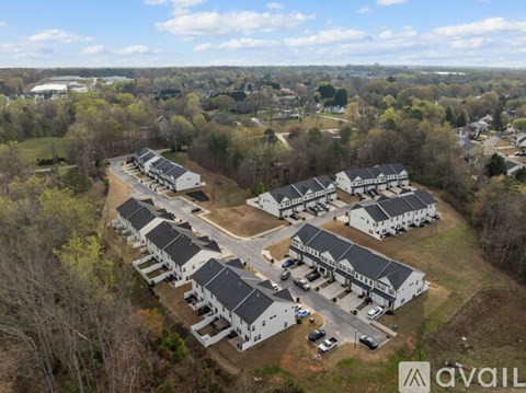 A bird's eye view of a housing complex with multiple buildings and cars parked in front.