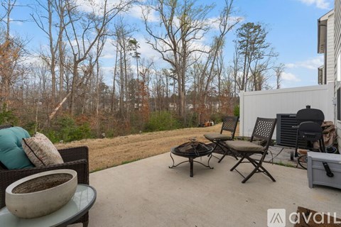 A patio with a table, chairs, and a cooler.
