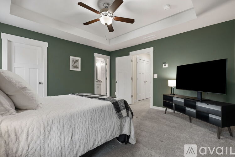 A bedroom with a bed, a dresser, and a ceiling fan.