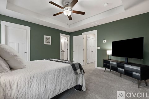 A bedroom with a bed, a dresser, and a ceiling fan.