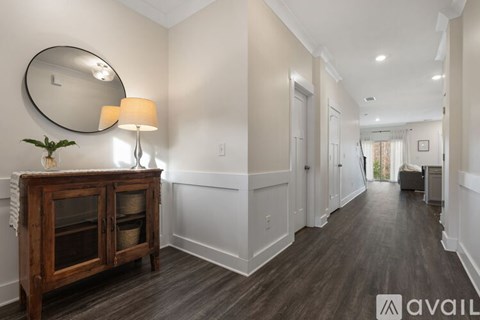 A hallway with a wooden cabinet and a round mirror on the wall.
