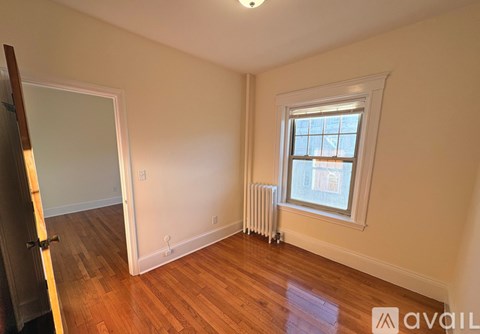 A room with a window and a radiator on the floor.