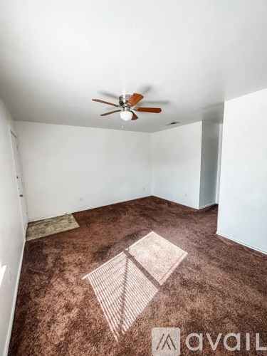 A room with a ceiling fan and carpeted floor.
