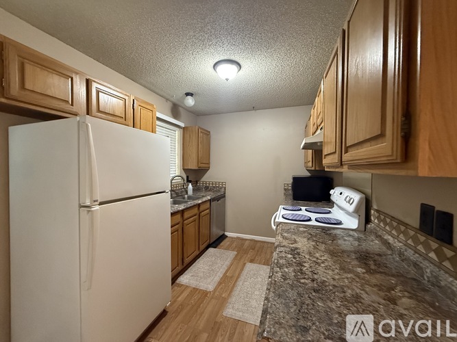 A kitchen with a white refrigerator and wooden cabinets.