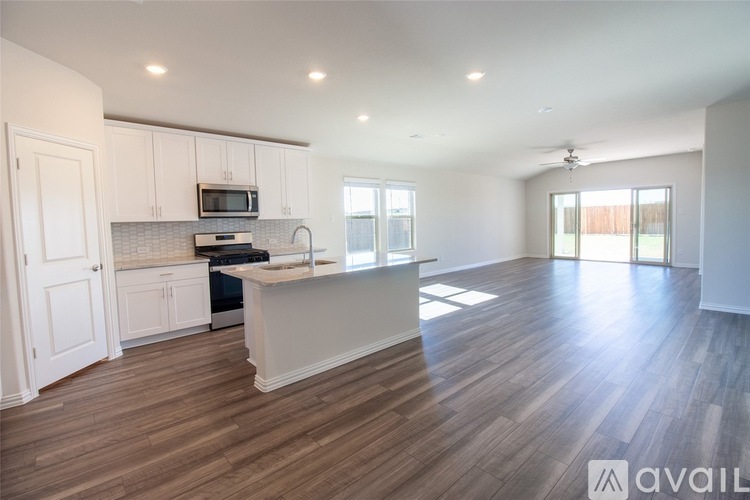 A spacious kitchen with white cabinets and a wooden floor.