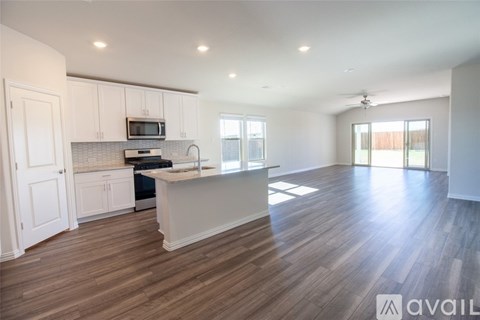A spacious kitchen with white cabinets and a wooden floor.