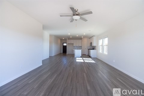 A spacious room with wooden flooring and a ceiling fan.