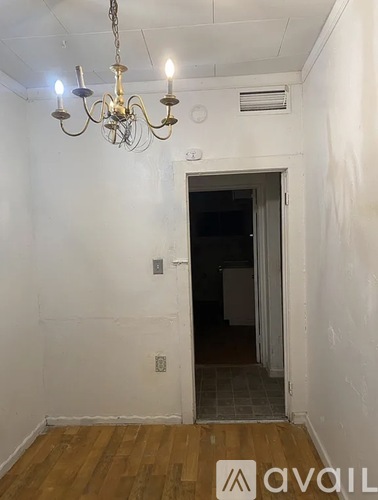 A room with a chandelier and a door leading to another room.