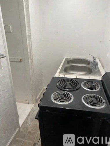 A black stove top oven with four burners sits in a small kitchen.