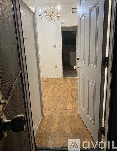 A hallway with a chandelier and a closed door.