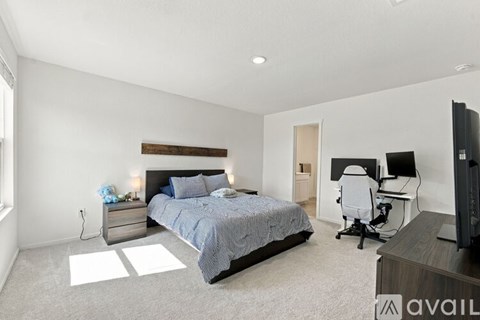 A bedroom with a bed, desk, and television.