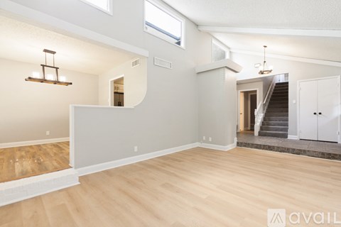A spacious living room with wooden flooring and a staircase leading to another level.