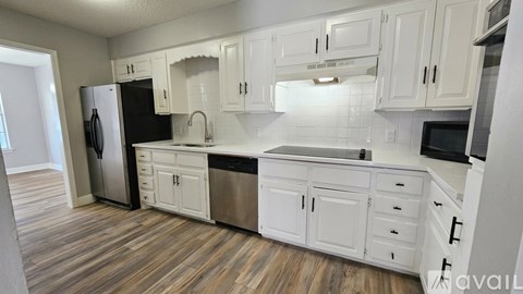 A kitchen with white cabinets and a black fridge.
