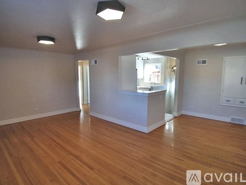 A spacious room with wooden floors and a large mirror on the wall.