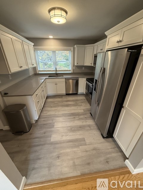 A kitchen with white cabinets and a stainless steel refrigerator.