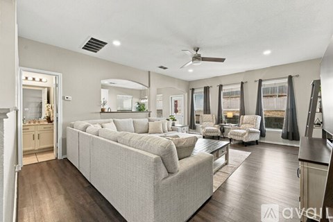 A spacious living room with a grey sofa and a wooden floor.