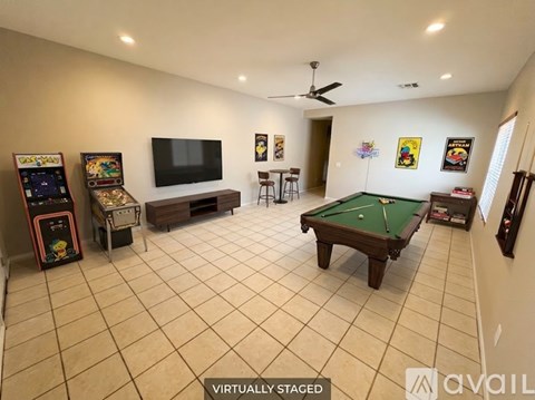 A room with a pool table, a television, and a pinball machine.