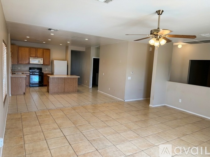 A spacious living room with a kitchen in the background.