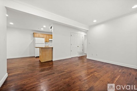 A spacious room with wooden floors and white walls.