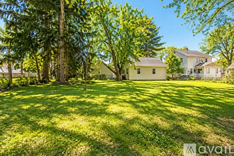 A grassy area with trees and houses in the background.