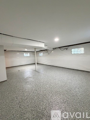 A spacious room with a grey carpet and white walls.
