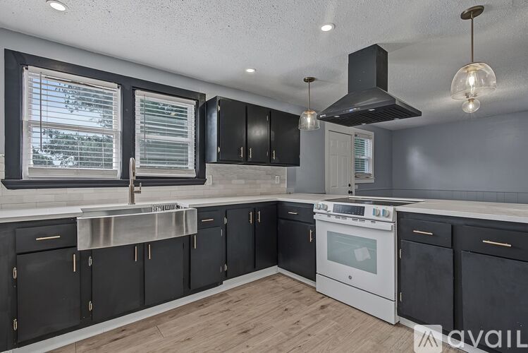 A kitchen with black cabinets and a white stove top oven.