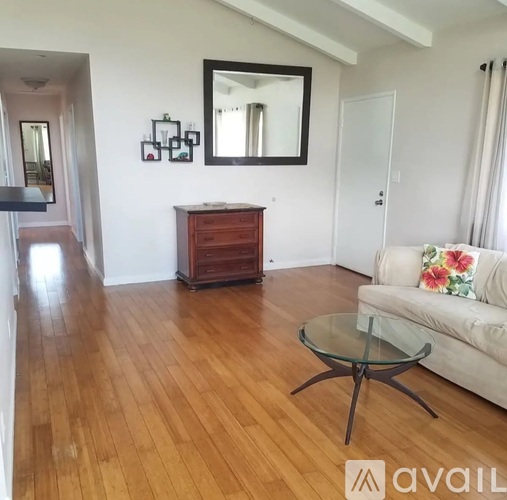 A living room with a white couch and a glass coffee table.