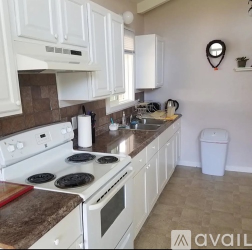 A kitchen with white cabinets and a white stove top oven.