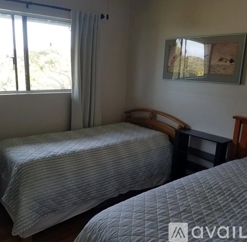 A bedroom with two beds and a window with curtains.