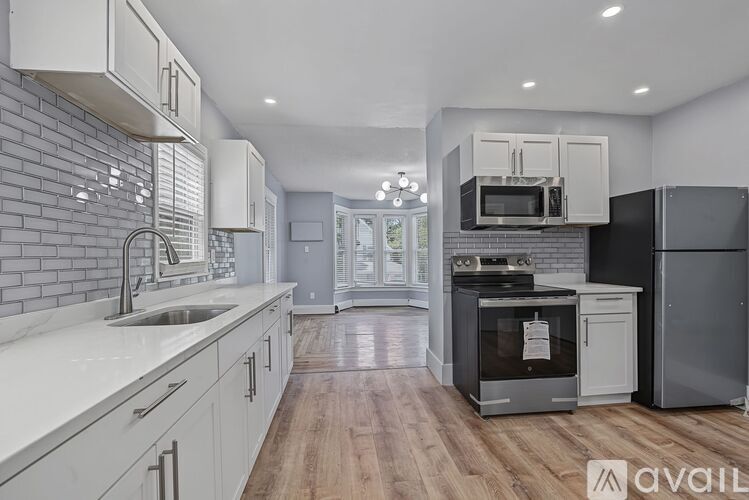 A modern kitchen with white cabinets and a brick wall backsplash.