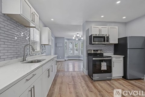 A modern kitchen with white cabinets and a brick wall backsplash.