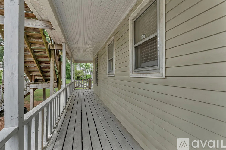 A wooden deck with a railing and a house with a window.