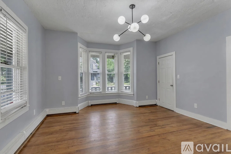 A spacious room with wooden floors and a ceiling fan.