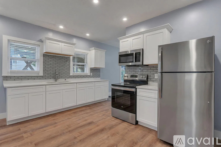 A kitchen with white cabinets and a stainless steel refrigerator.
