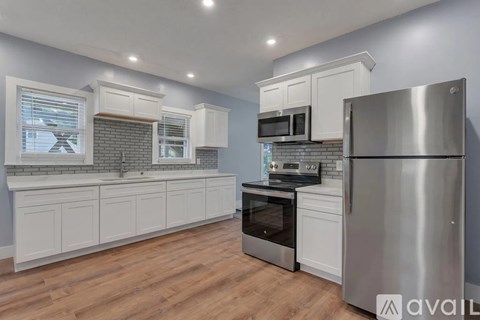 A kitchen with white cabinets and a stainless steel refrigerator.