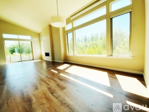 A spacious room with wooden floors and large windows.